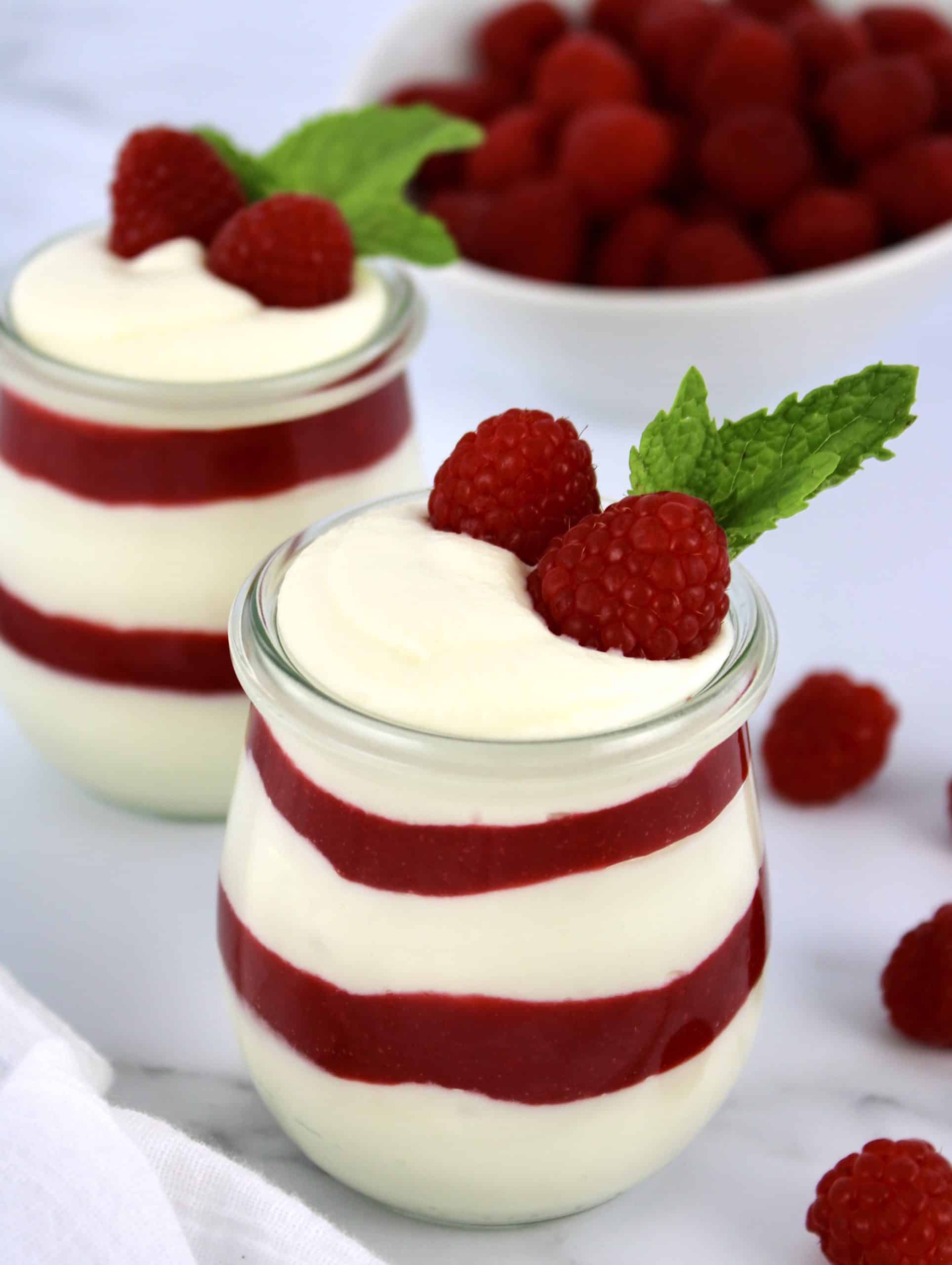 white chocolate mousse with raspberry sauce layers in two glass jars