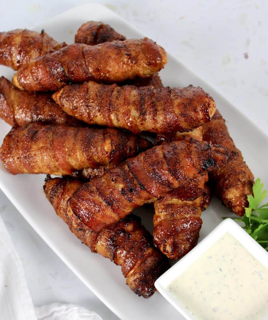 Bacon Wrapped Air Fryer Chicken Tenders on white plate with ranch on side