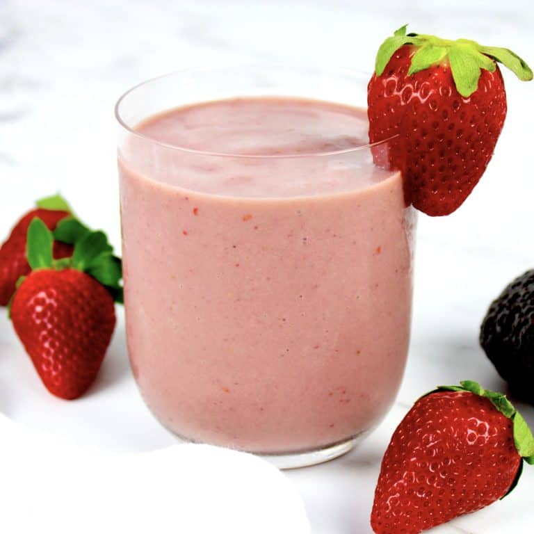 berry avocado smoothie in glass with strawberry on side of glass