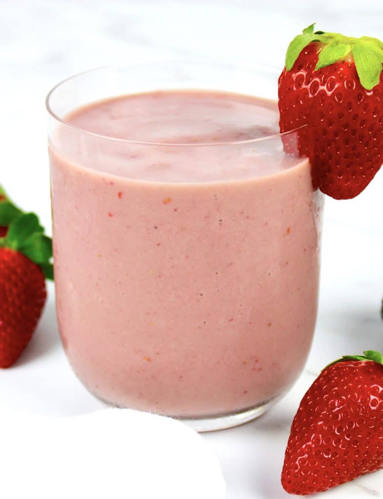berry avocado smoothie in glass with strawberry on side of glass