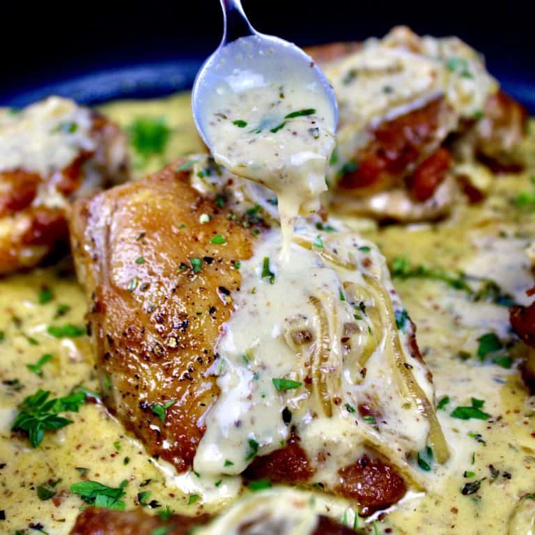 chicken dijon in skillet with sauce being spooned over top
