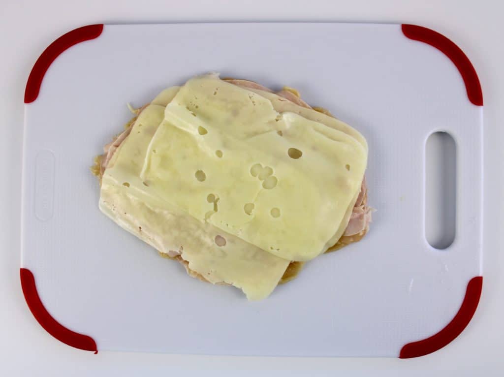 slices of cheese on chicken on cutting board
