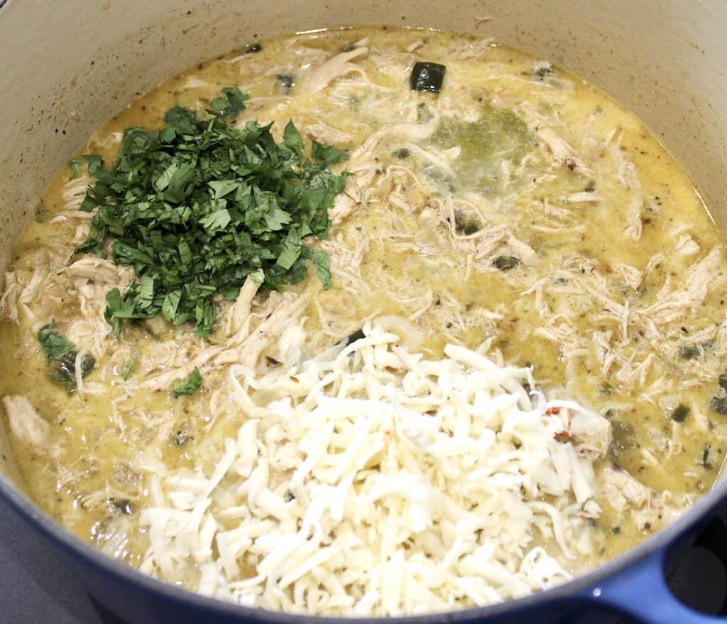 white chicken chili with shredded cheese and cilantro on top
