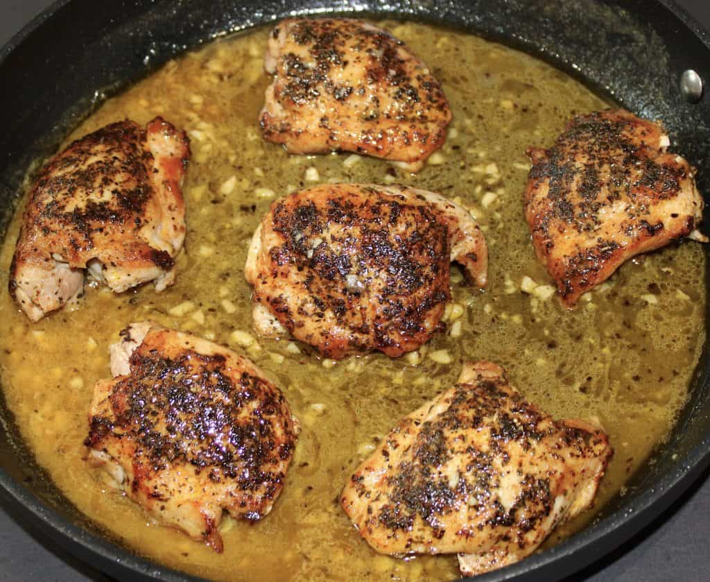 6 cooked chicken thighs in skillet with lemon butter sauce