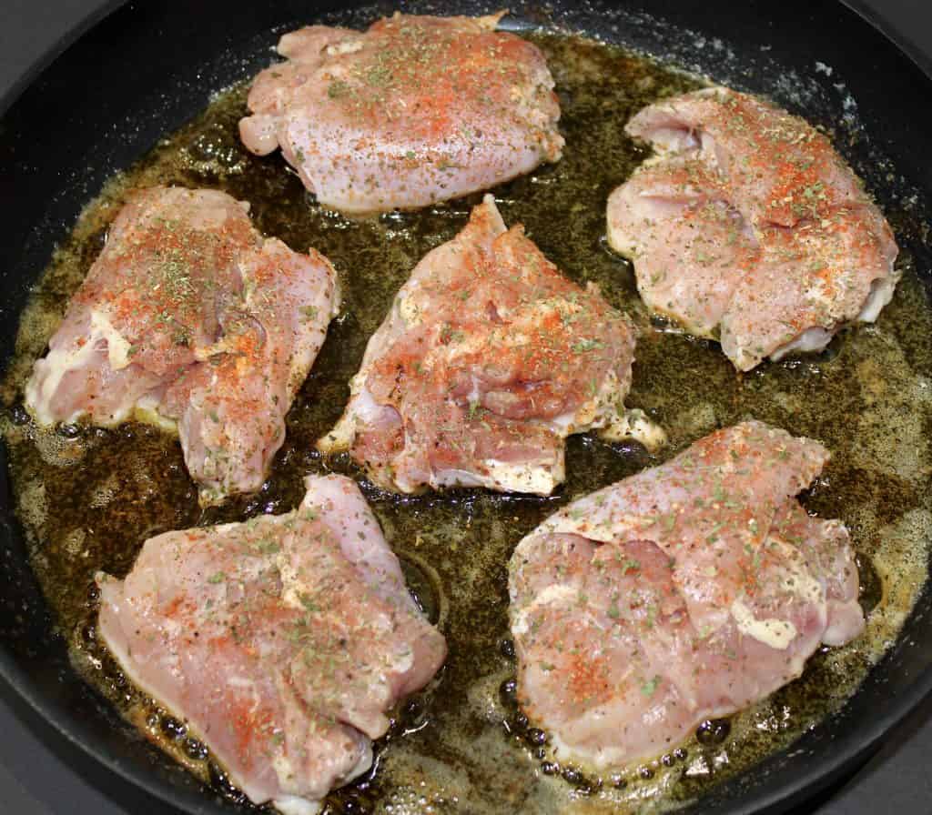 6 raw chicken thighs in skillet with spices on top
