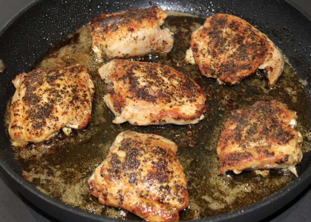 6 chicken thighs in skillet with spices on top