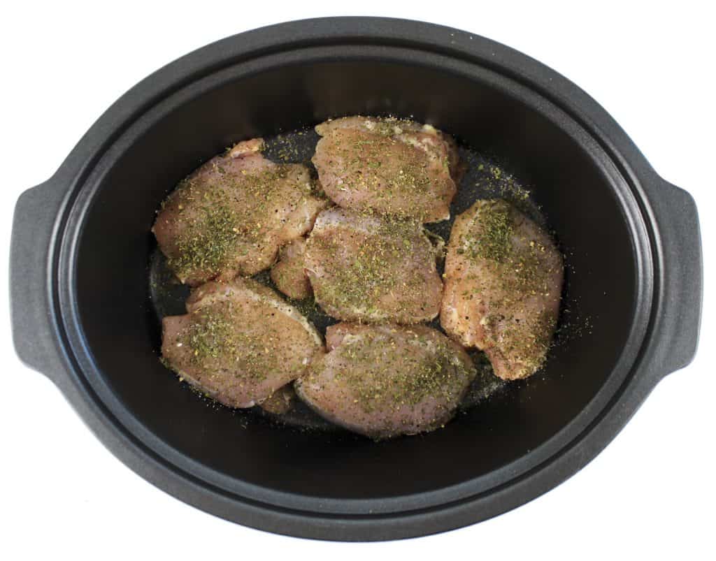 raw chicken thighs in crockpot with spices on top