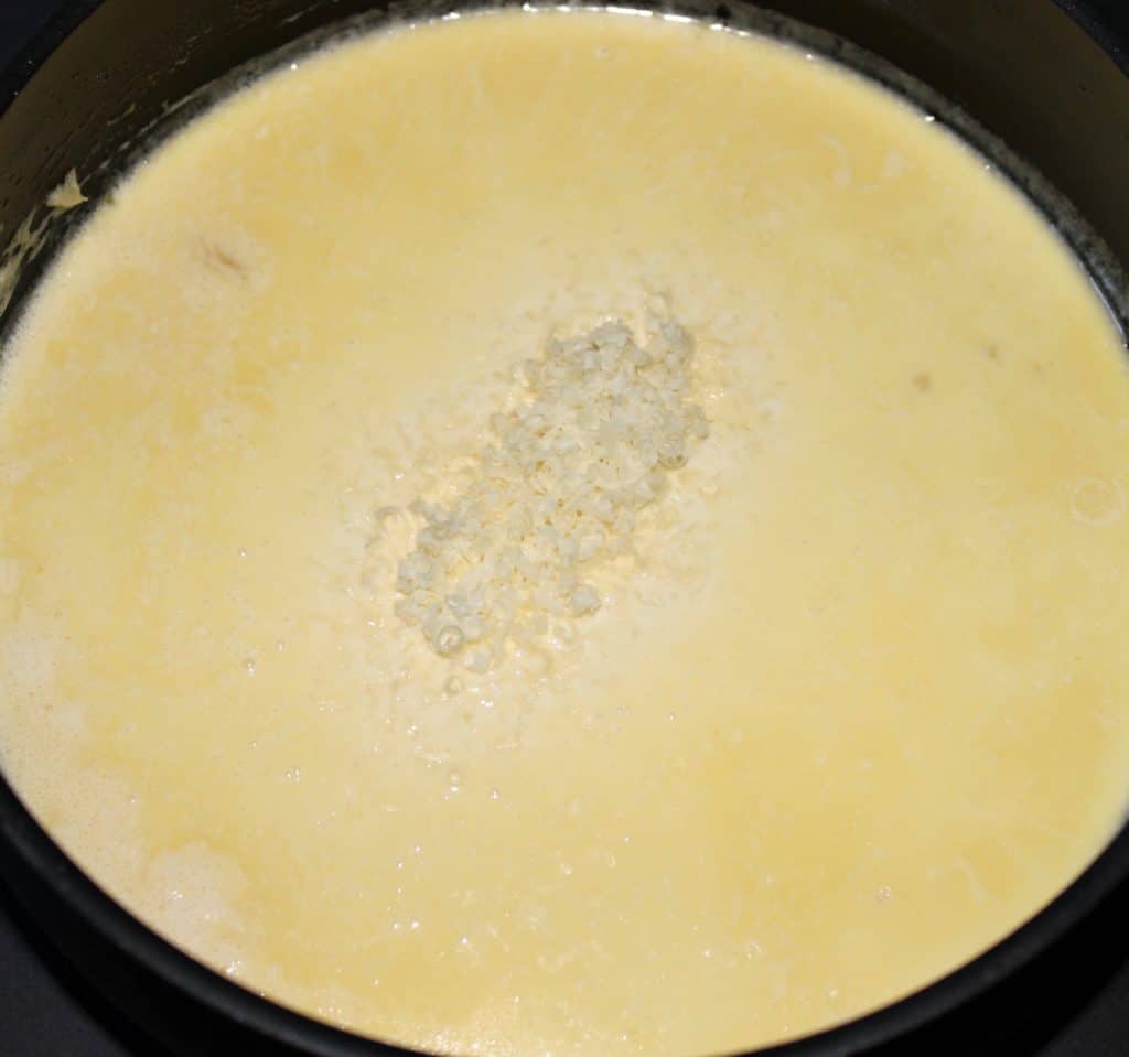 cream sauce with grated parmesan cheese in saucepan