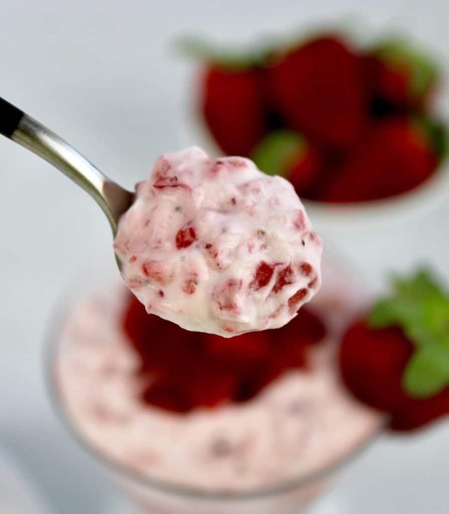 closeup of Strawberries and Cream in spoon with strawberries in background