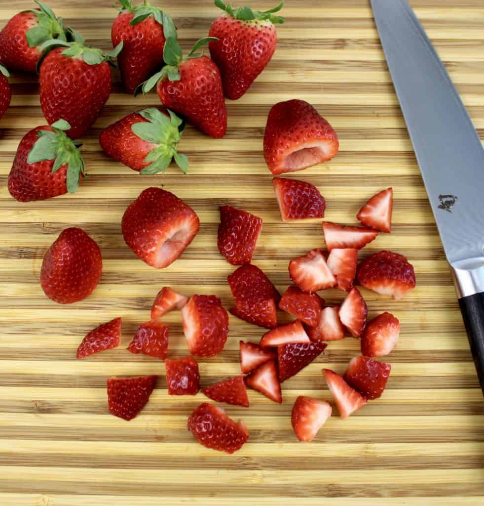 chopped strawberries on cutting board with knife