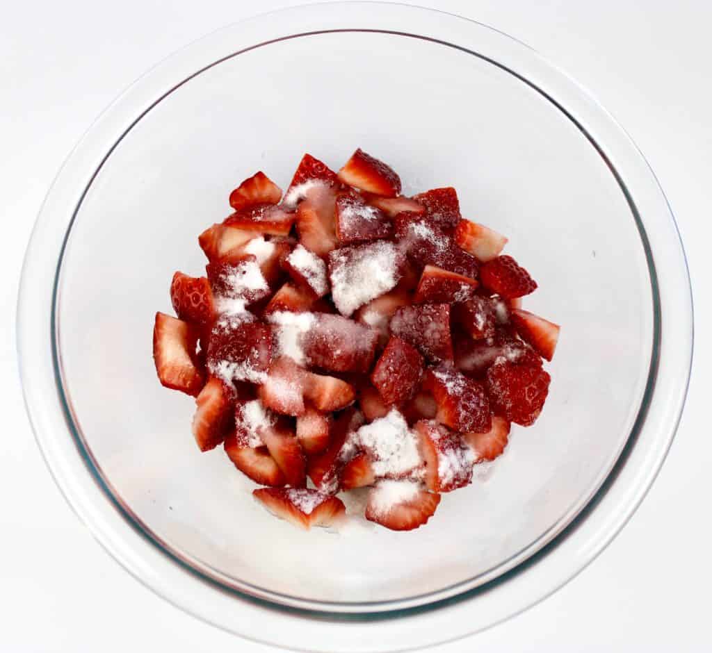 diced strawberries in glass bowl with sugar on top