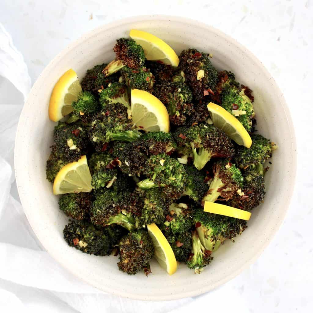 overhead view of Air Fryer Broccoli in white bowl with lemon slices