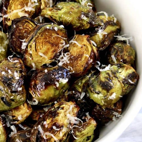 Air Fryer Brussels Sprouts in white bowl with grated cheese on top