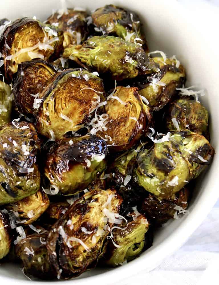 Air Fryer Brussels Sprouts in white bowl with grated cheese on top