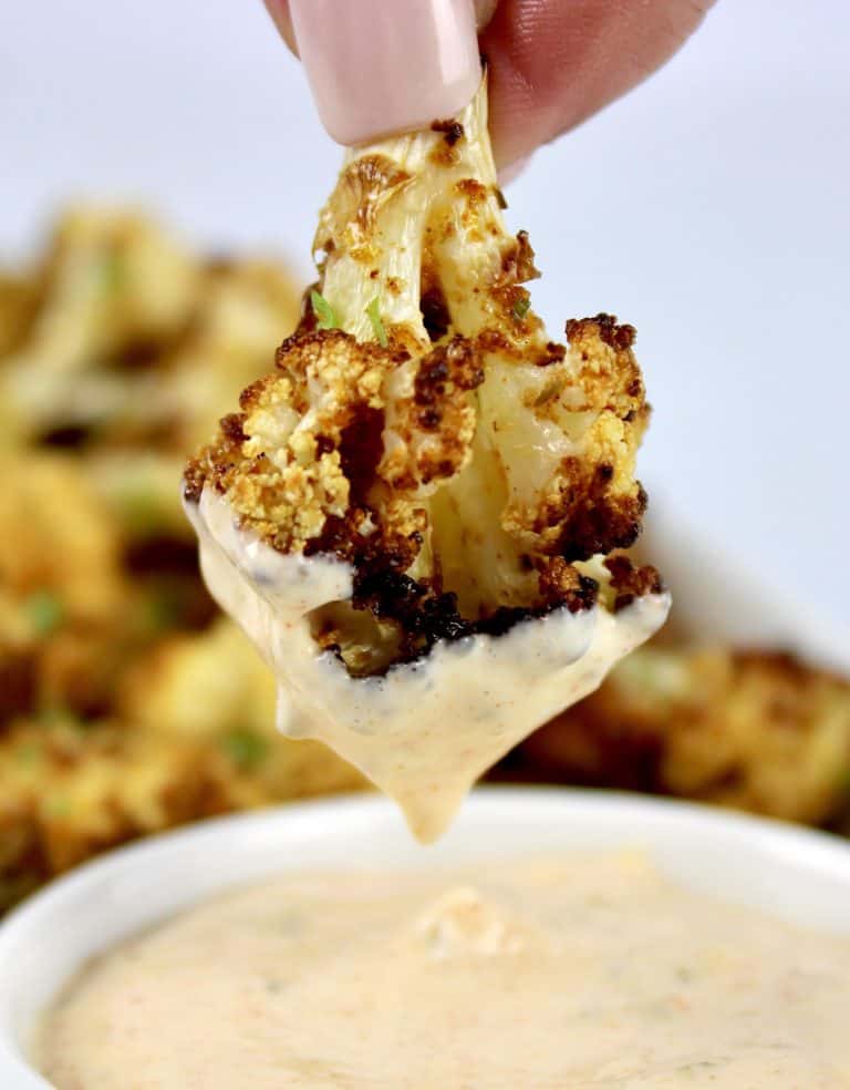 air fryer cauliflower being dipped into sauce