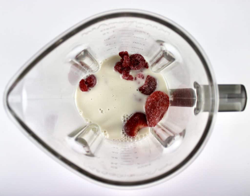 frozen berries and almond milk in blender bowl