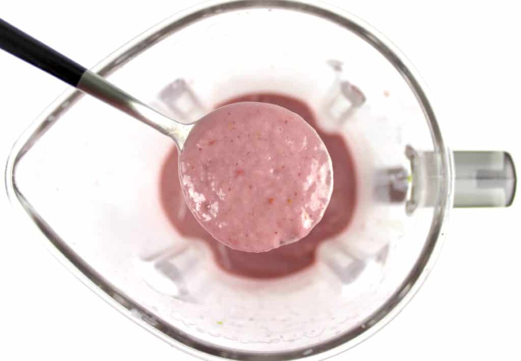 berry avocado smoothie in spoon over blender bowl
