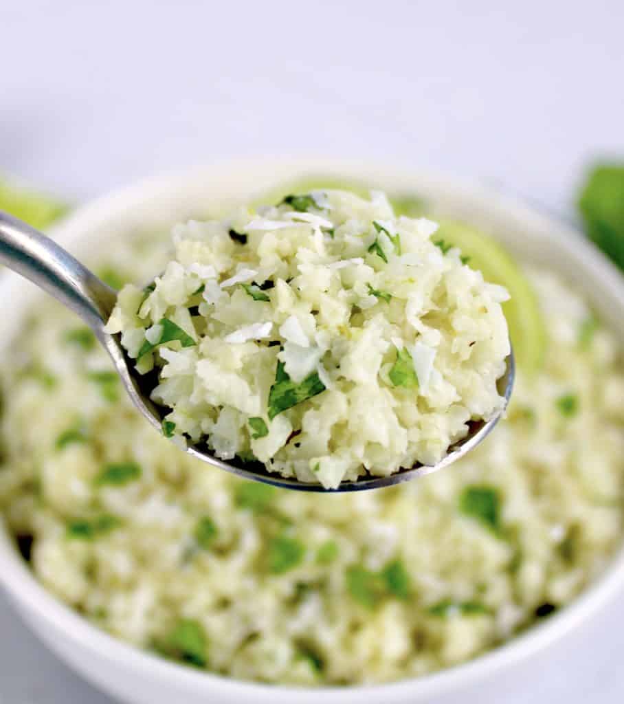 closeup of spoonful of Coconut Cauliflower Rice over white bowl