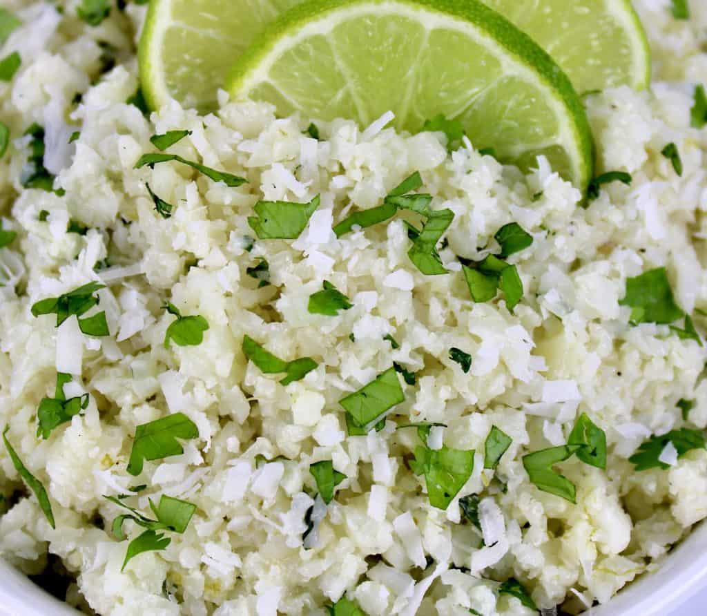 closeup of Coconut Cauliflower Rice in white bowl with lime slices on top