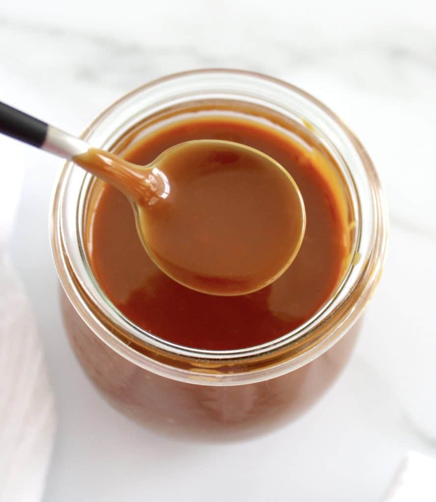 overhead view of Salted Caramel Sauce with spoon over glass jar