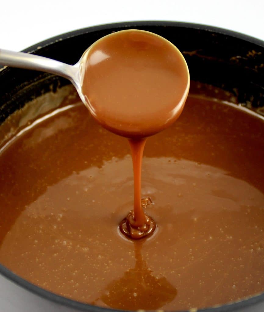 caramel sauce being dripped from spoon over saucepan