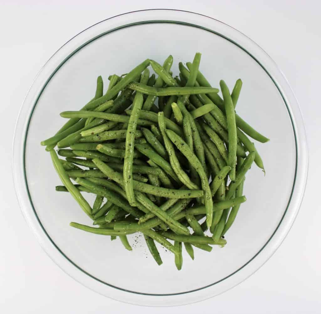 green beans with salt pepper and olive oil in glass bowl