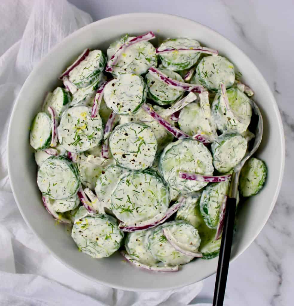 Creamy Cucumber Salad in white bowl with spoon