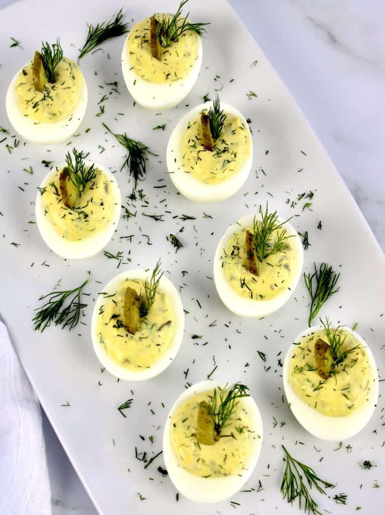 Dill Pickle Deviled Eggs on white plate with dill garnish