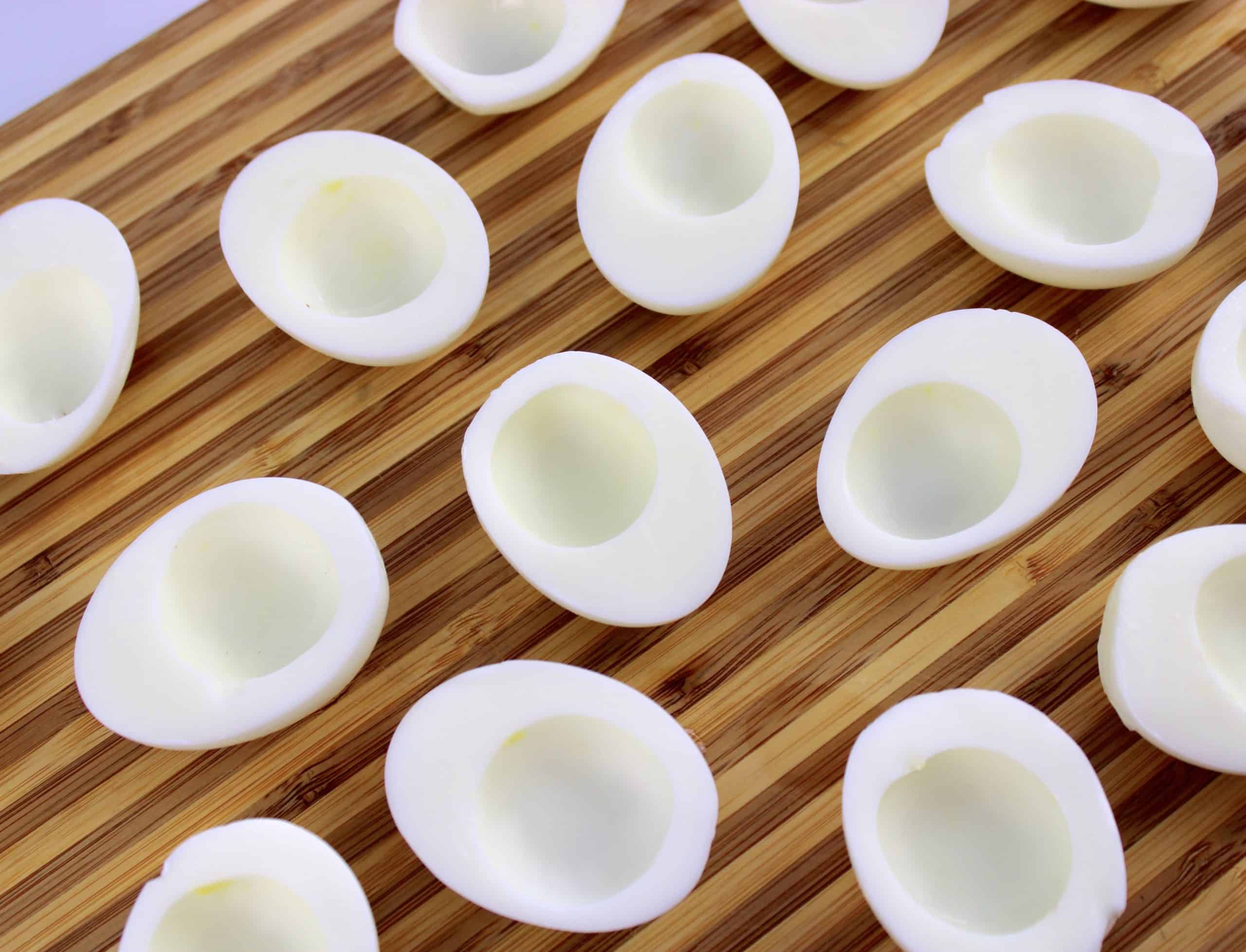 halves of hard boiled eggs on cutting board without yolks