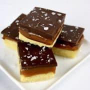 4 caramel slice squares stacked on white plate