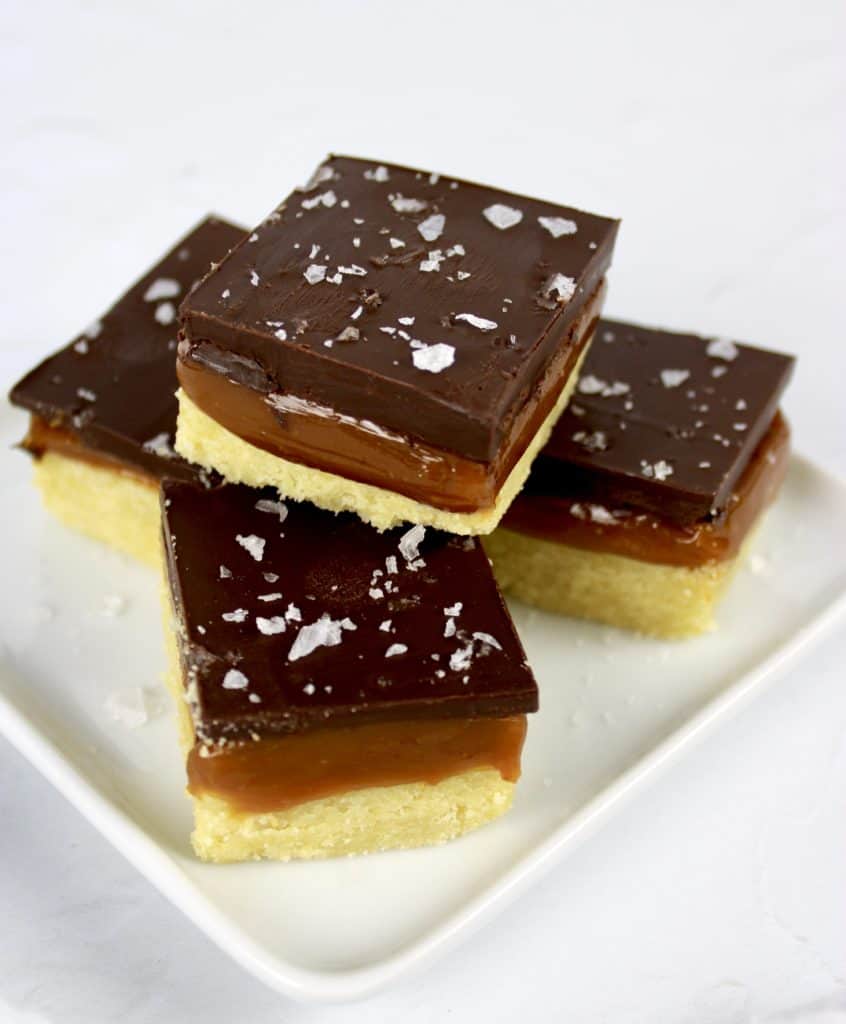 4 caramel slice squares stacked on white plate