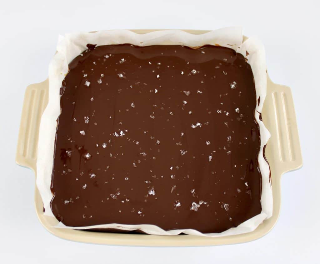 chocolate layer of Caramel Slice in baking dish with flaked salt on top