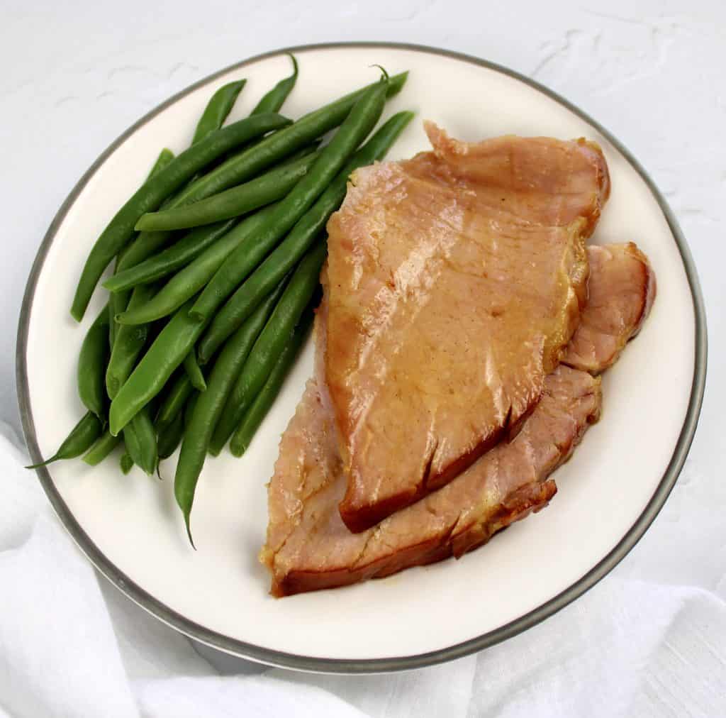 2 slices ham and green beans on white plate