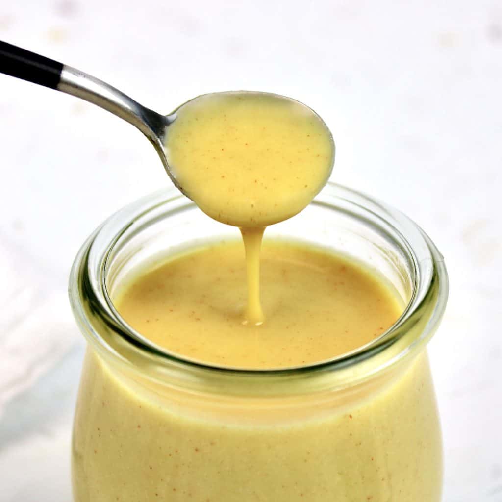 Keto Honey Mustard Sauce in jar dripping from spoon