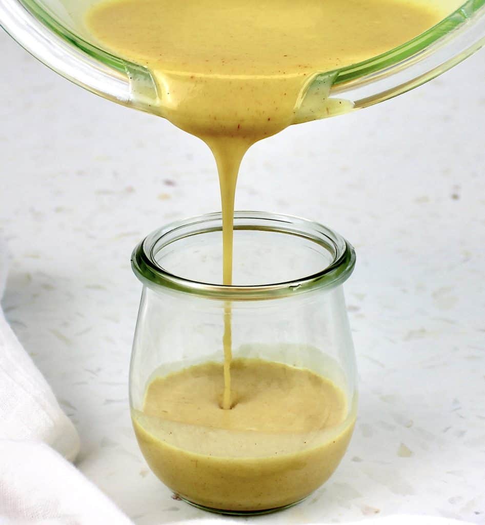 Keto Honey Mustard Sauce being poured into glass jar