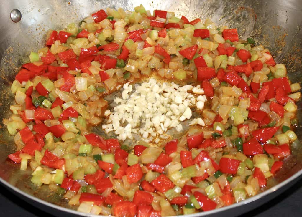 diced celery onion red pepper in skillet and garlic in the center