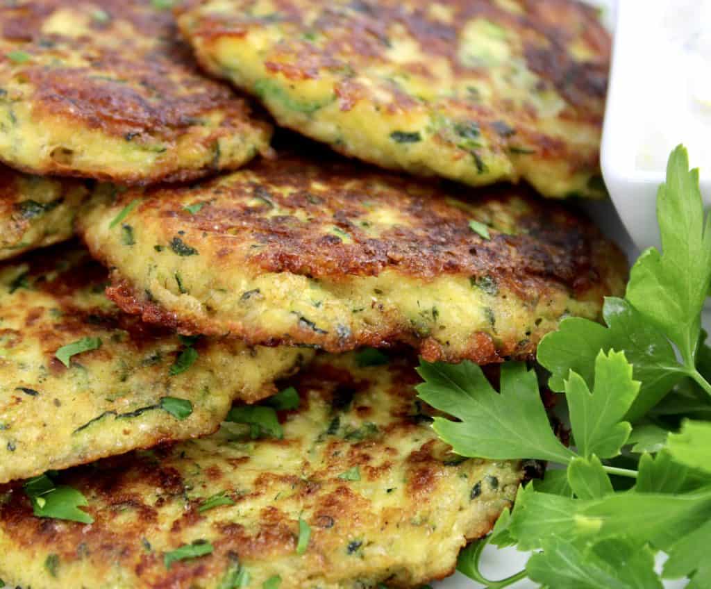 Keto Zucchini Fritters piled up on plate with parsley on side