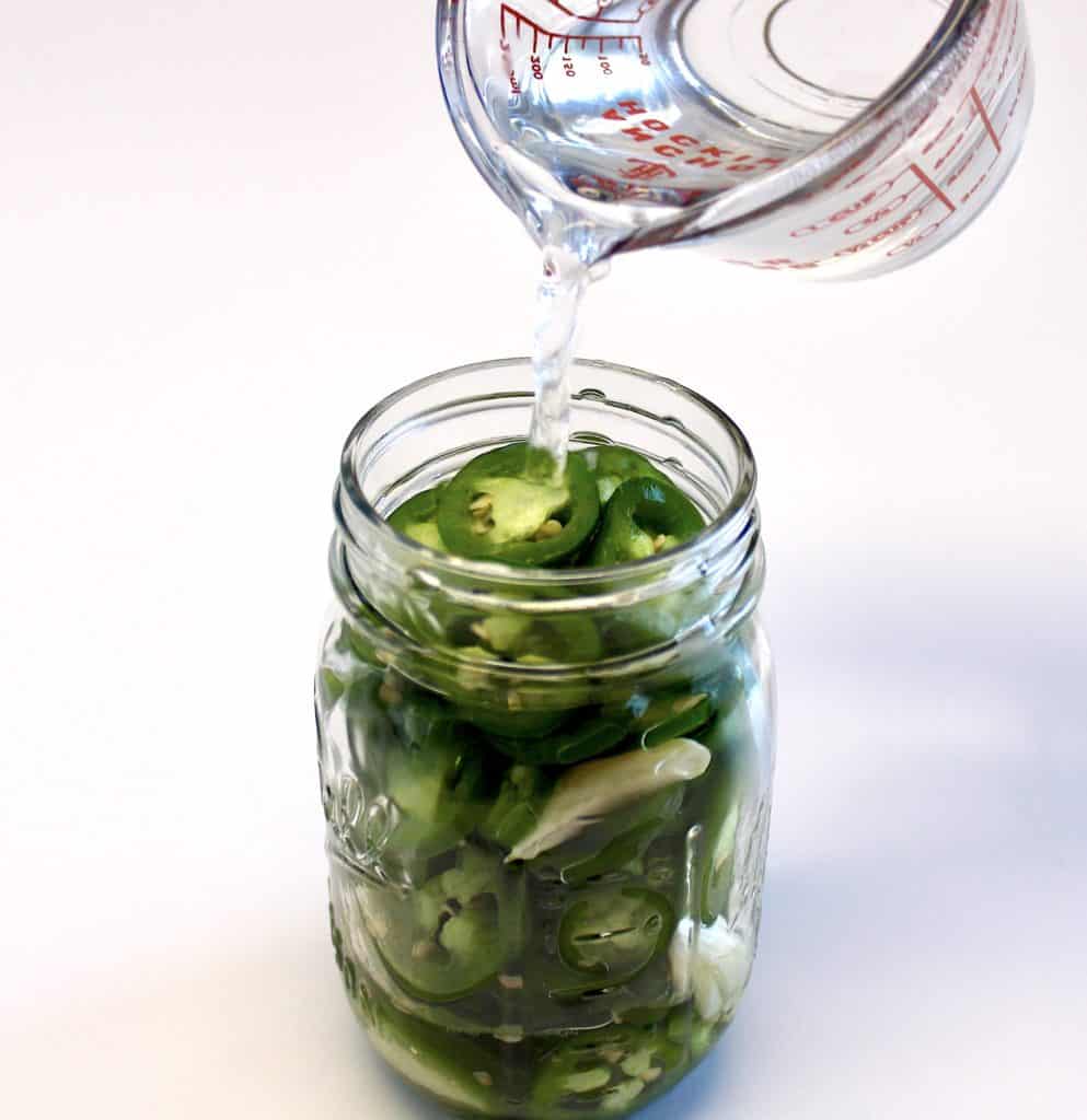 water being pour into jar with jalapeno peppers