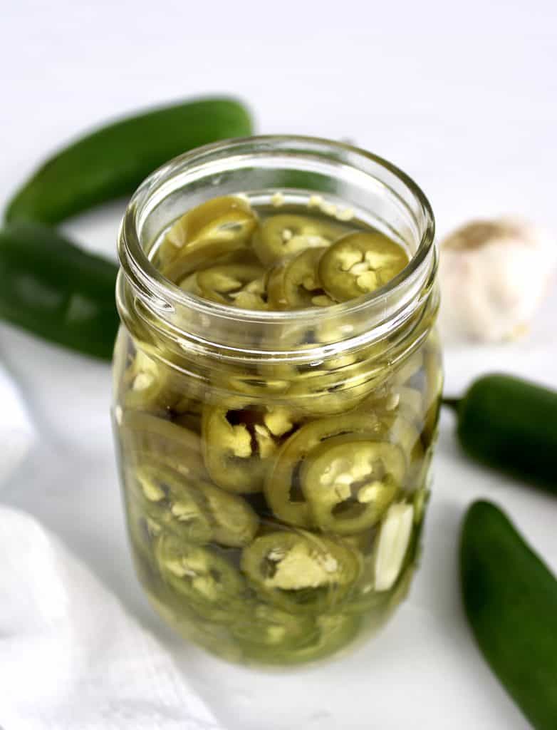 Pickled Jalapeños with jalapenos and garlic in background