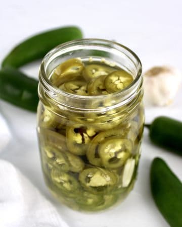 Pickled Jalapeños with jalapenos and garlic in background