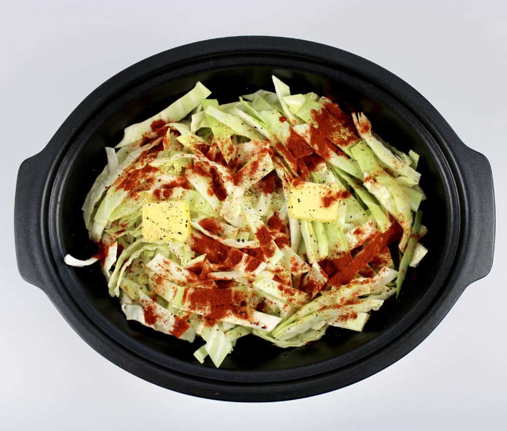 raw shredded cabbage with butter and spices in slow cooker