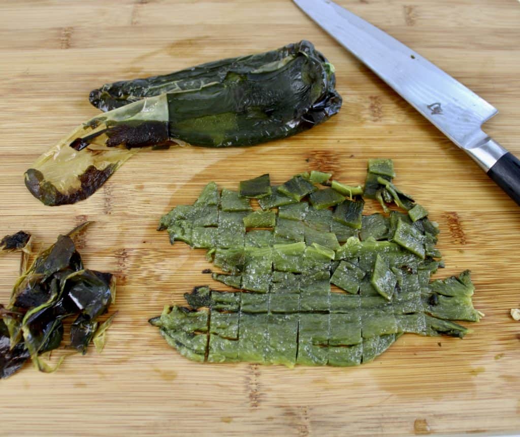 roasted poblano on cutting board with knife diced