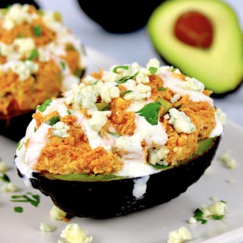 buffalo chicken stuffed avocado with blue cheese on top and avocado in background