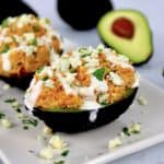 buffalo chicken stuffed avocado with blue cheese on top and avocado in background
