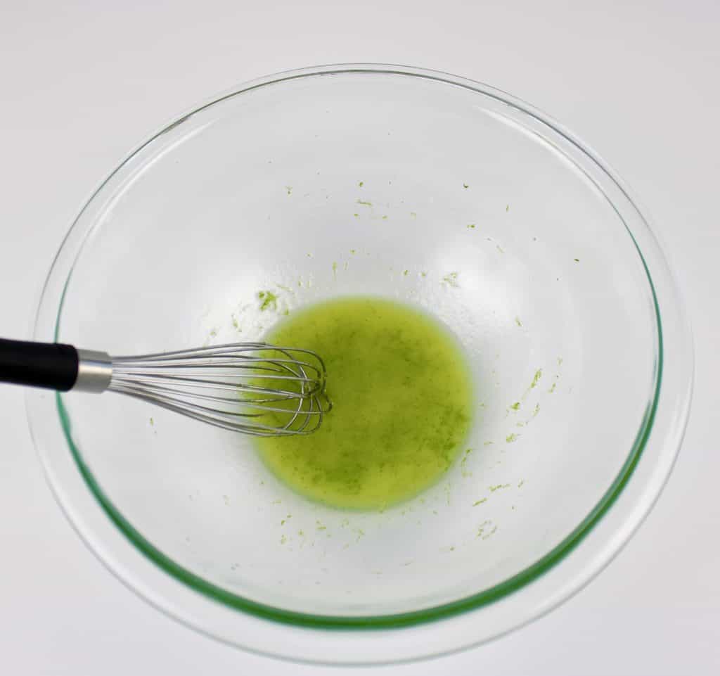 olive oil and lime with whisk in glass bowl