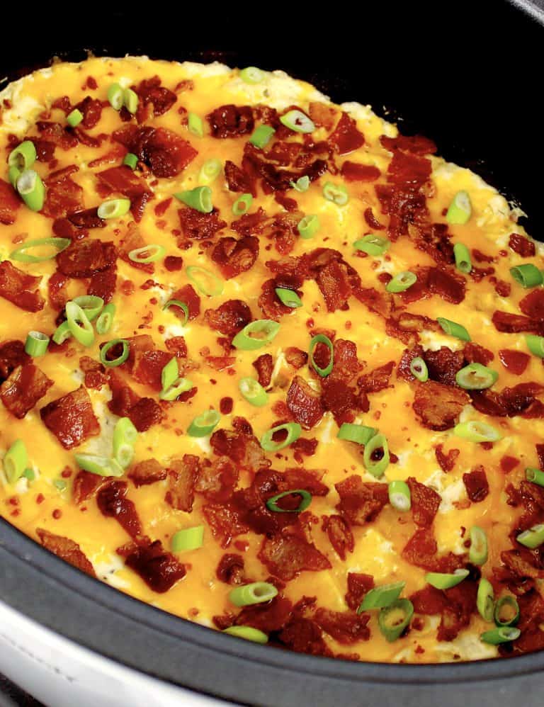 ranch chicken in crock pot with melted cheese and bacon on top