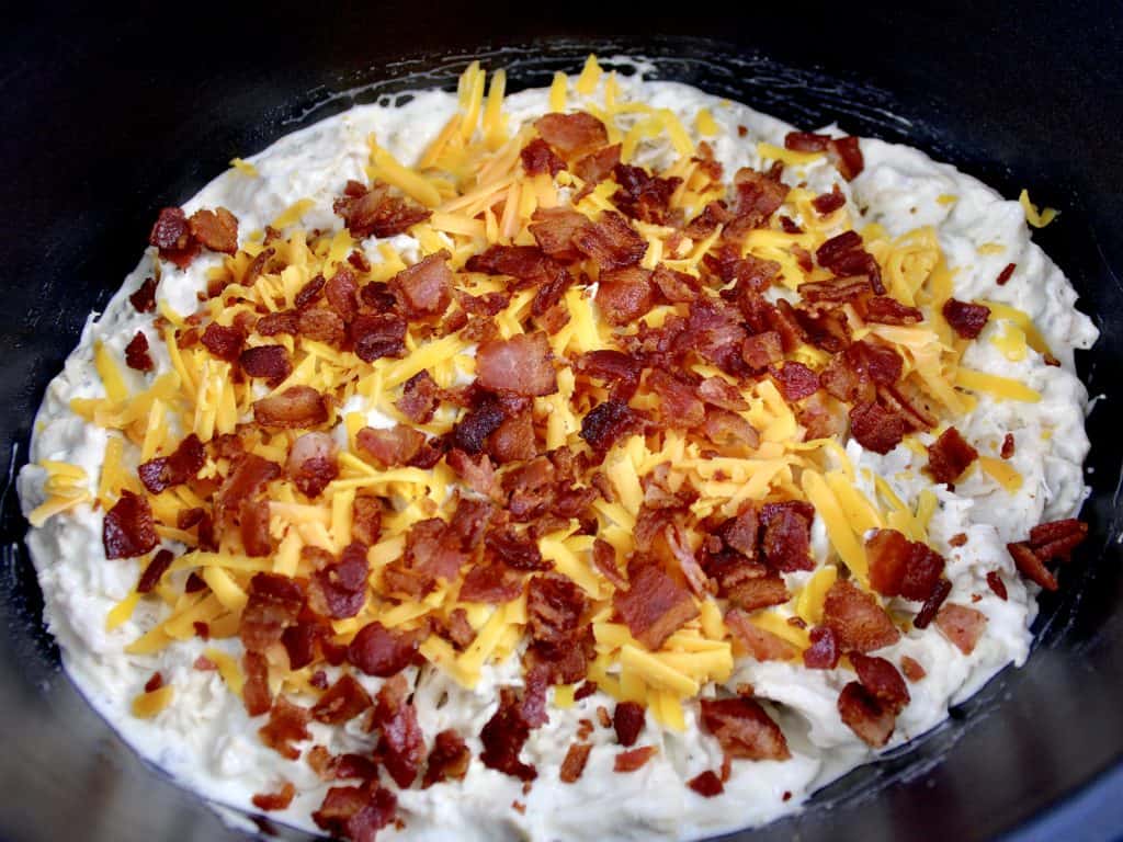 creamy ranch chicken in crockpot with shredded cheddar and bacon