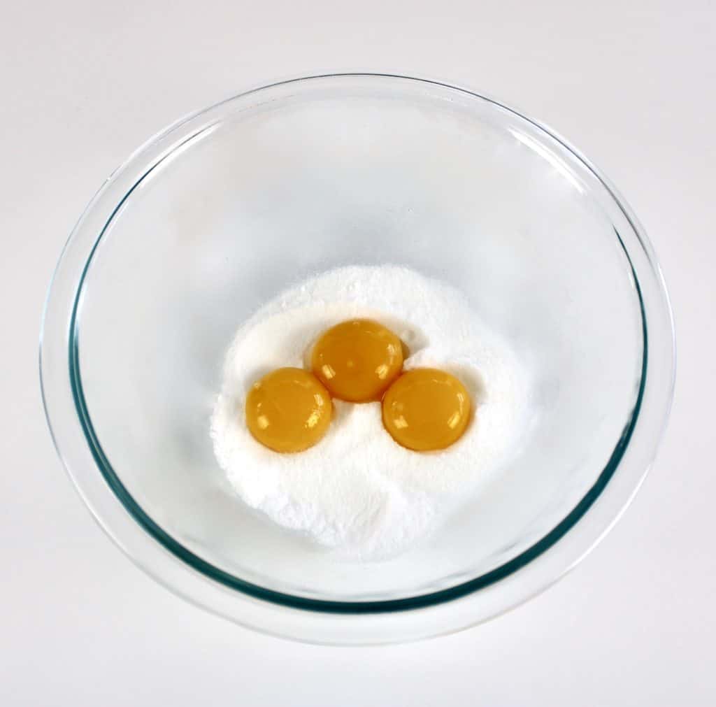 sugar and 3 egg yolks in glass bowl