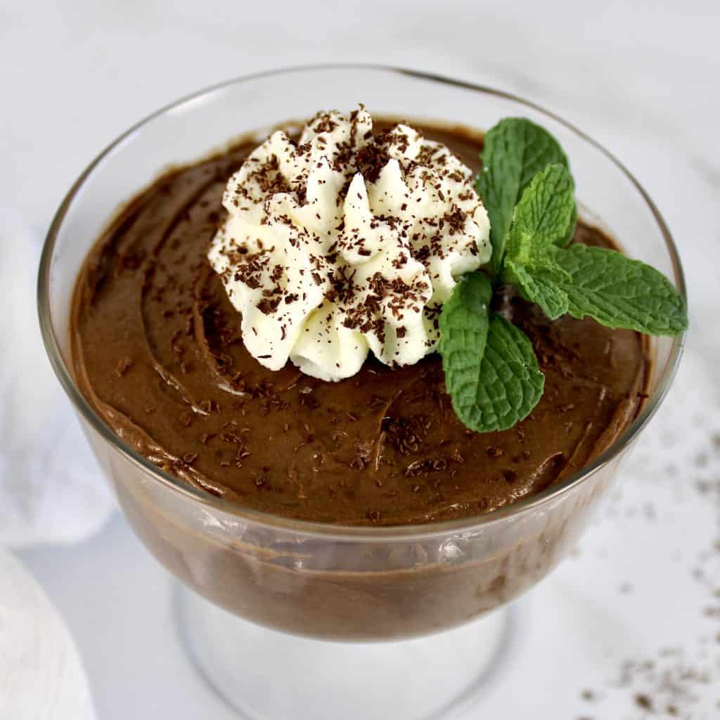 chocolate pudding in glass with whip cream and sprig of mint