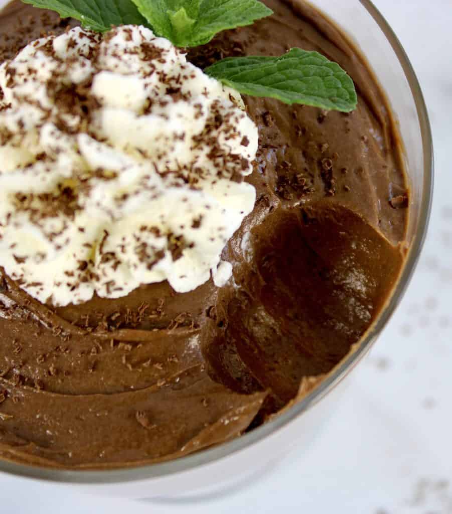 closeup of chocolate pudding with whip cream on top and spoonful missing